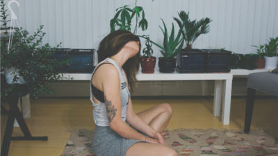 a woman sitting on the floor in a living room with furniture and plants around her